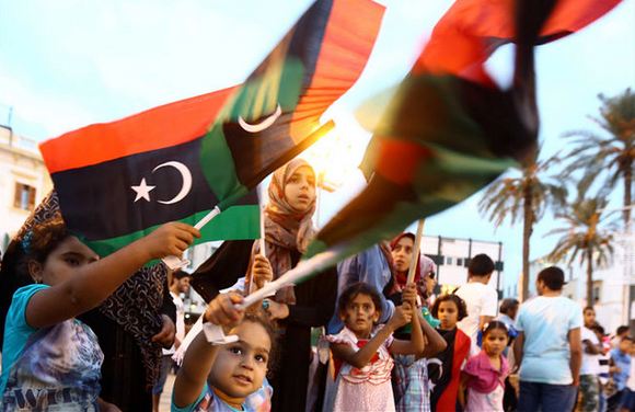  ليبيون يلوحون بالعلم الوطني في طرابلس. أ ف ب/ محمود تركية