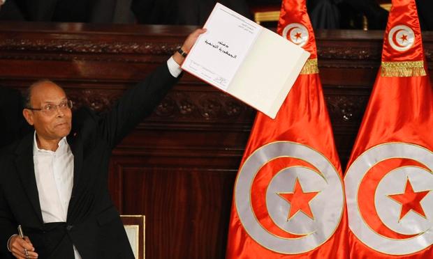 Tunisia's president, Moncef Marzouki, holds a copy of the new constitution after signing it before deputies in the national assembly on Monday. Photograph: Anis Mili/Reuters Tunisia's president, Moncef Marzouki, holds a copy of the new constitution after